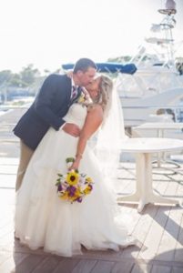 The bride and groom kissing on the docks.